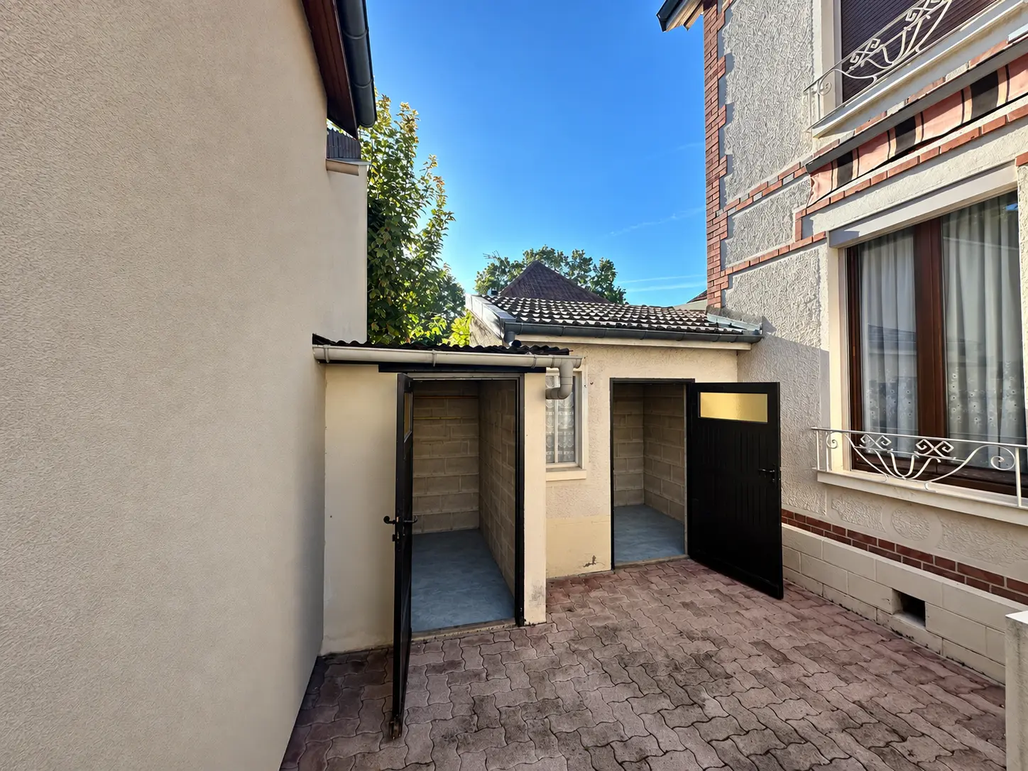 Cour pavée avec appentis et abris à portes noires